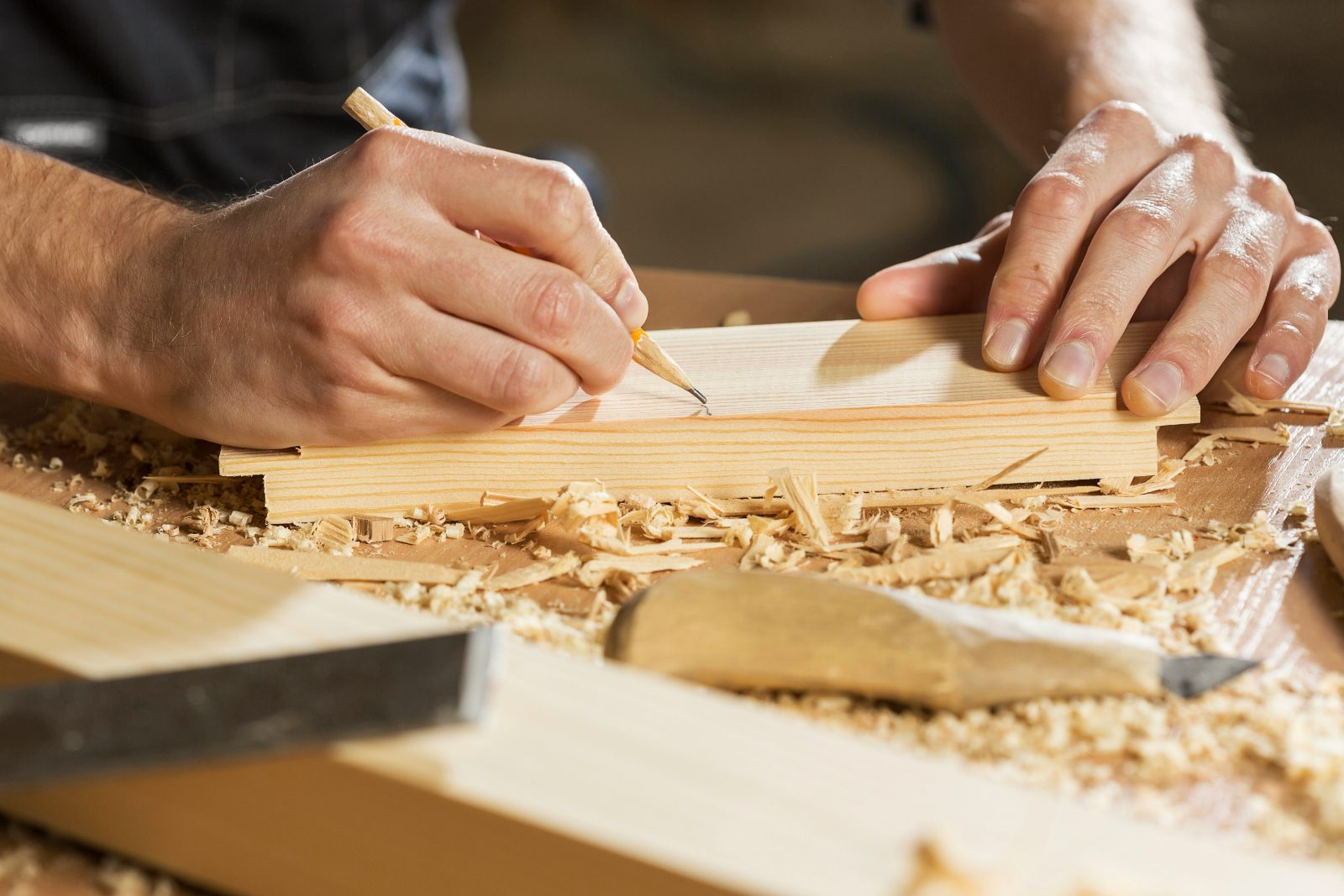 Tischler zeichnet ein Holzbrett an